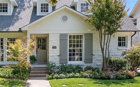 white house with grey metal.roof and.wood shutters|cedar shutters on white house.